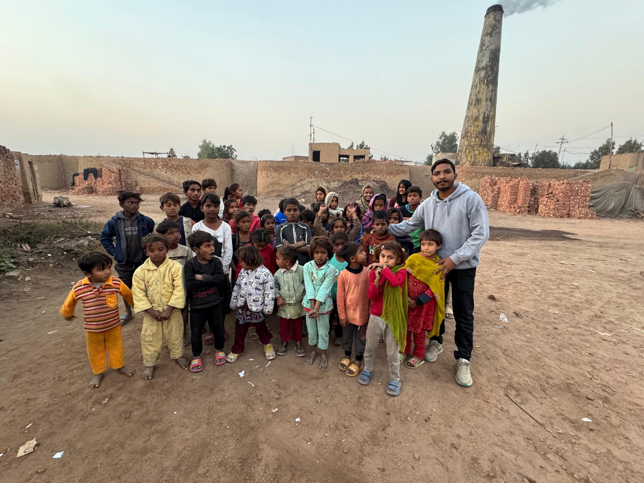 Children gathered with a ministry leader in a brick kiln community in Pakistan