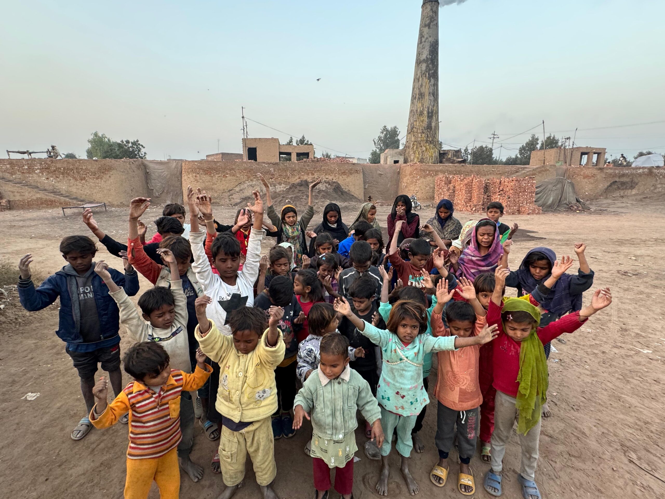 Children gathered with a ministry leader in a brick kiln community in Pakistan