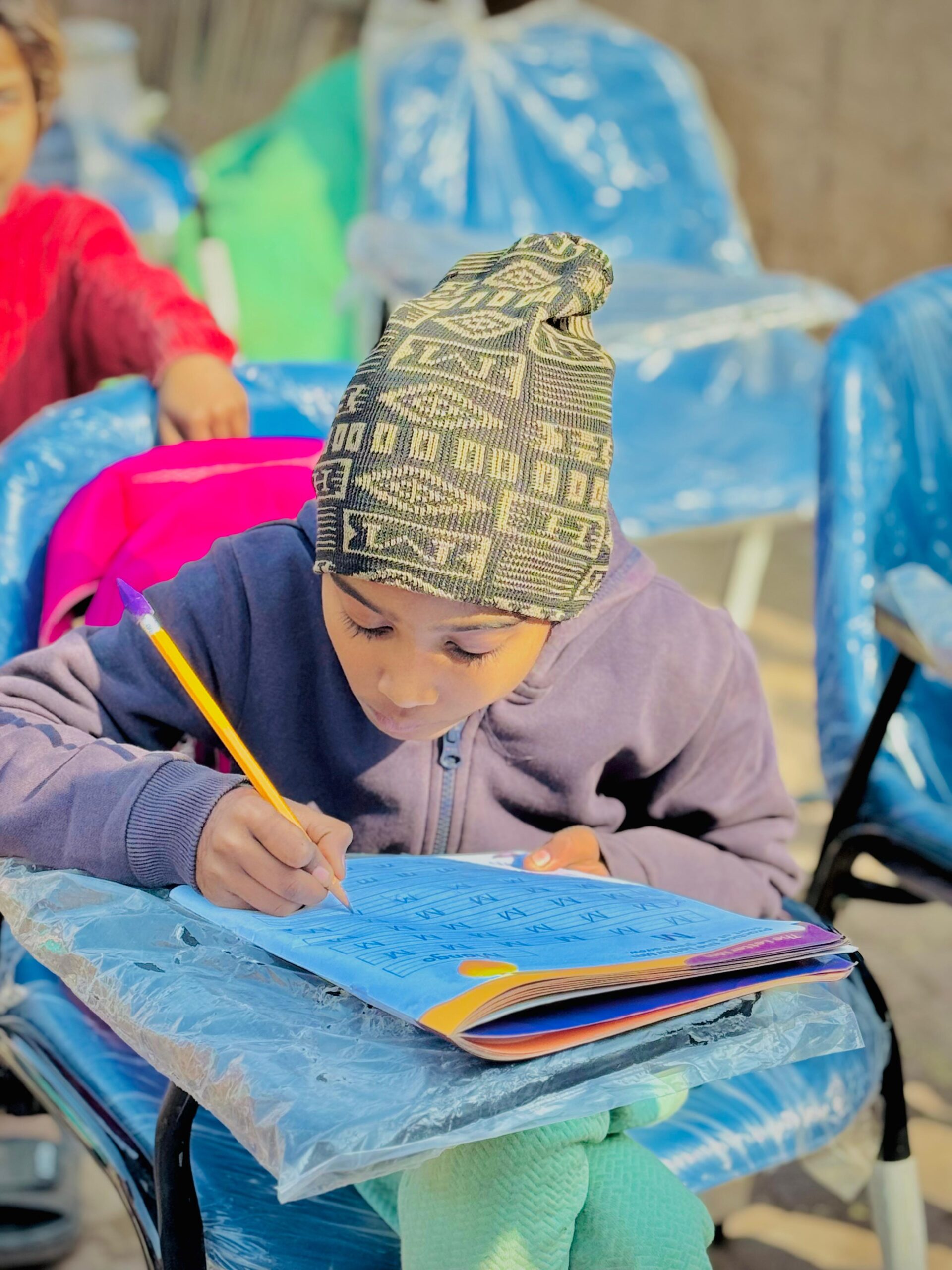 Child writing in a workbook during Kingdom First Mission education support