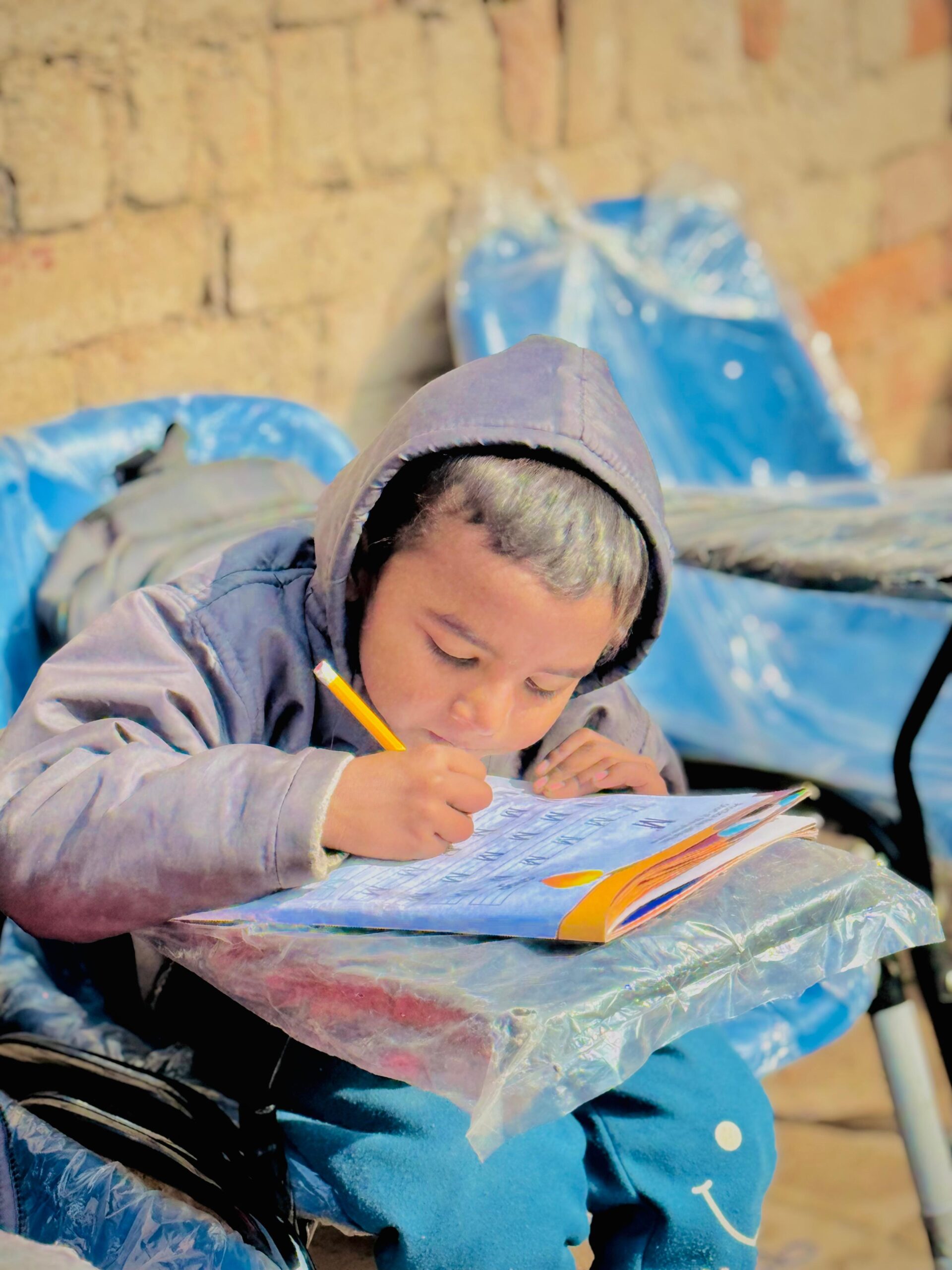 Young child writing during education support in Pakistan