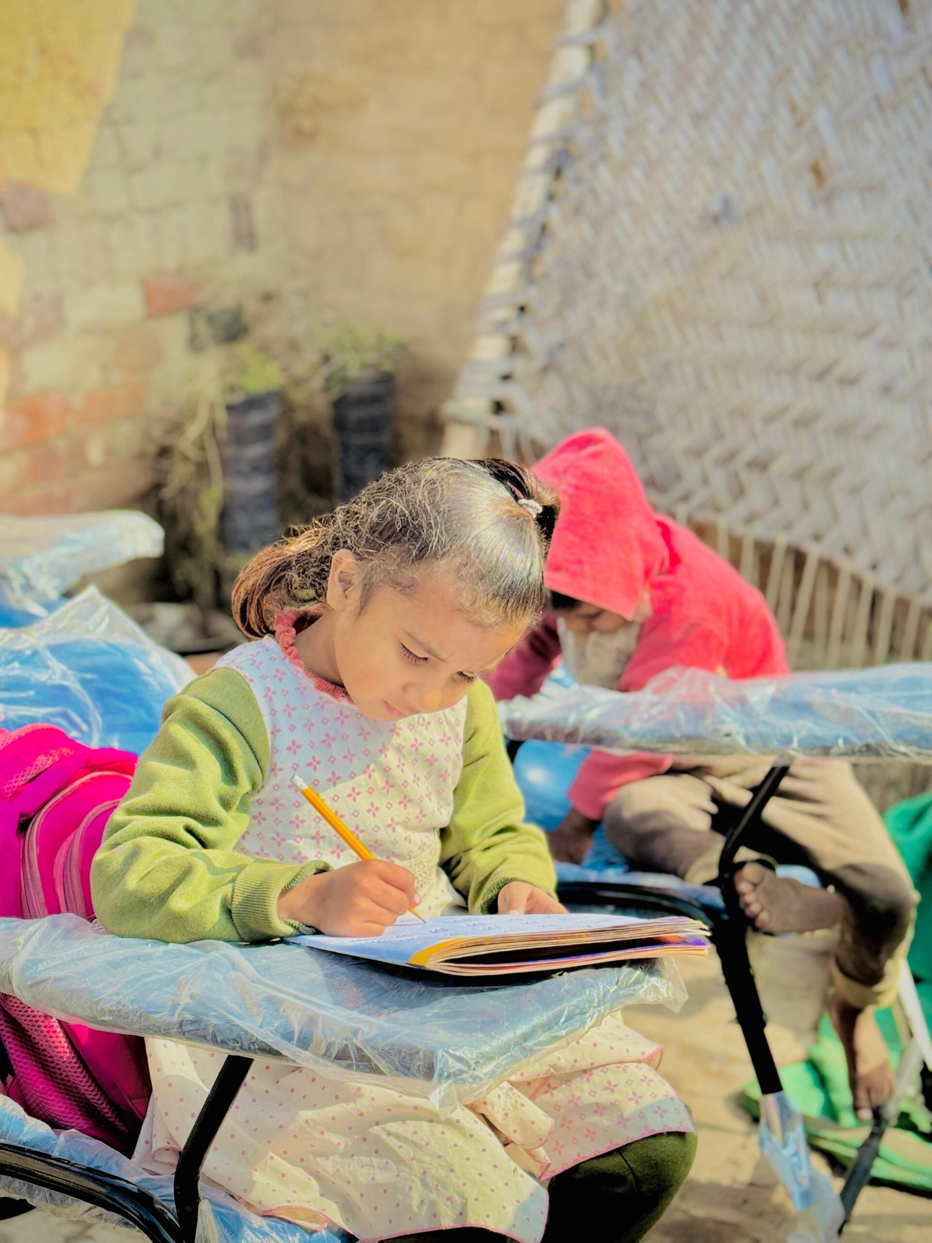 Young child writing in a workbook during Kingdom First Mission education support